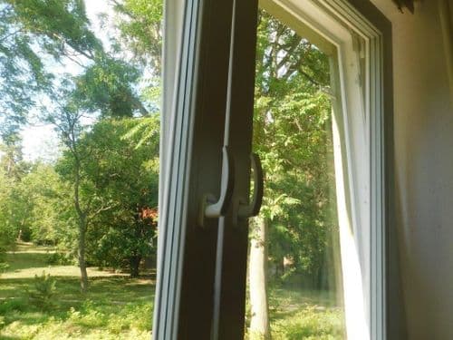 felújított ablakok bukóra nyitva, háttérben fák és bokrok